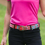 Woman wears ethno-woven-belt-for-women-happy-adriana-smitten with black pants and pink top.