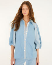 Front studio view of a model wearing the Farm Rio Bicolor Blue Fluid Denim Blouse, showcasing its light and mid-blue contrasting panels and relaxed fit.