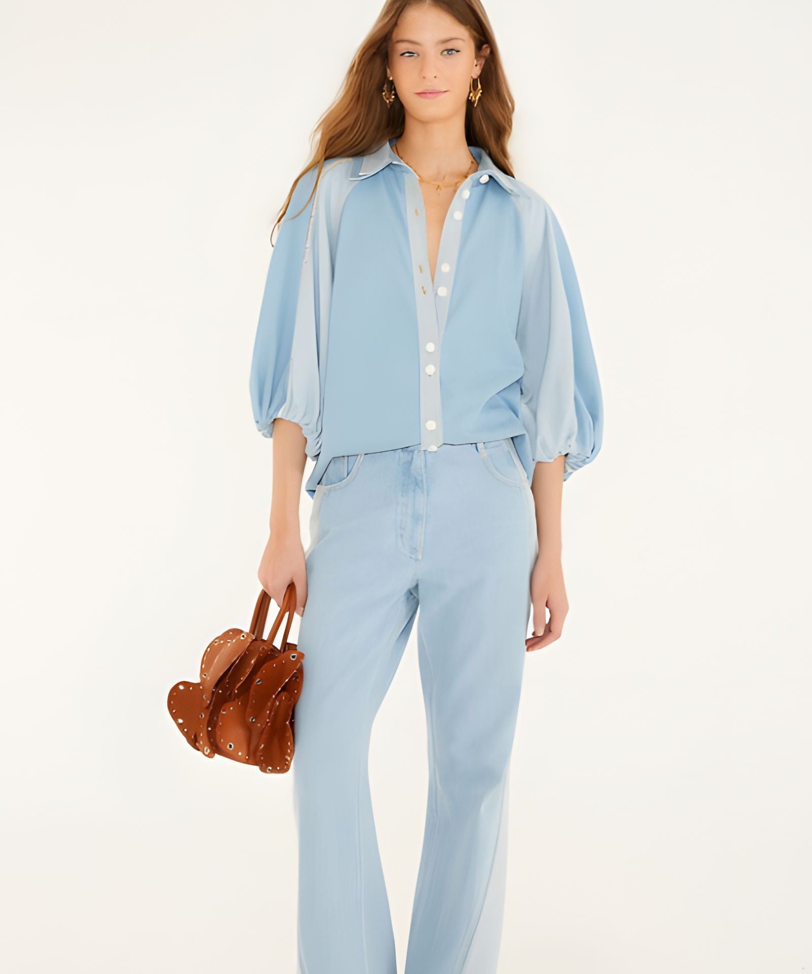 Full-length studio shot of a model styling the Farm Rio bicolor blue denim blouse with matching denim pants, holding a textured brown handbag.
