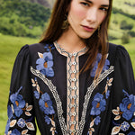 Medium portrait view of a model showcasing the detailed front bodice, lace open-work trims, and cinched waist of the Farm Rio embroidered midi dress.