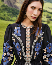 Medium portrait view of a model showcasing the detailed front bodice, lace open-work trims, and cinched waist of the Farm Rio embroidered midi dress.