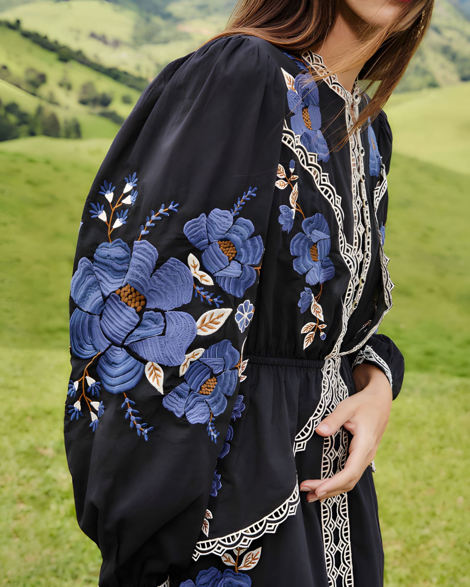 Close-up lifestyle view focusing on the billowing long sleeve of the Farm Rio dress, showcasing the vivid blue floral embroidery.