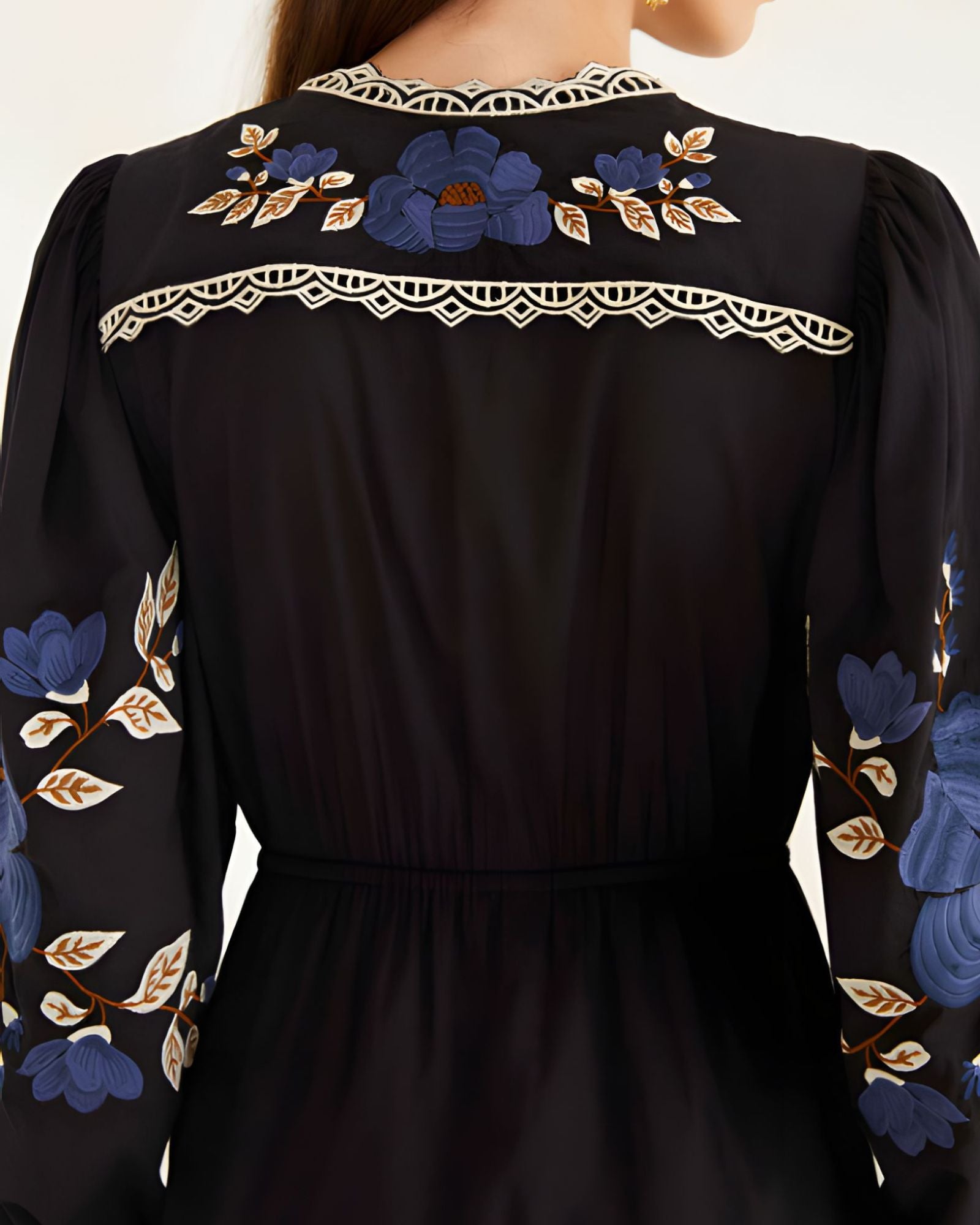 Close-up view of the Farm Rio Black Bold Flowers midi dress from behind, highlighting the intricate blue floral embroidery and geometric lace trim on the upper back yoke.