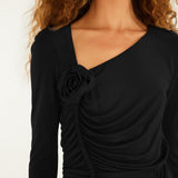 Close-up of the FARM Rio black jersey blouse: rosette at the asymmetric neckline and ruching down the front