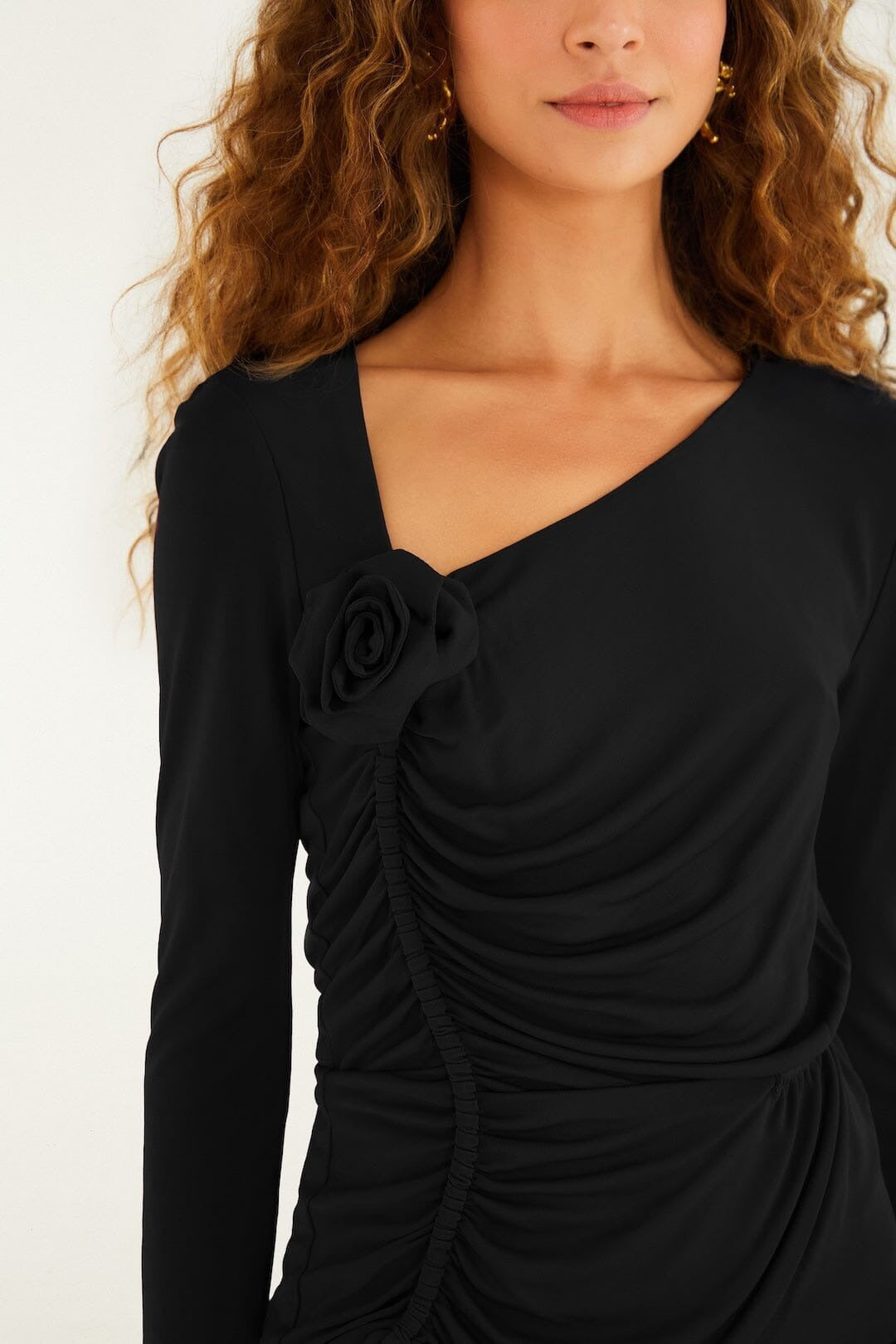 Close-up of the FARM Rio black jersey blouse: rosette at the asymmetric neckline and ruching down the front