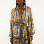 Front view of a model in a studio wearing the Farm Rio Blue Mosaic Garden belted mini dress with long sleeves.
