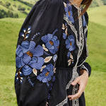 Close-up lifestyle view focusing on the billowing long sleeve of the FARM Rio dress, showcasing the vivid blue floral embroidery.