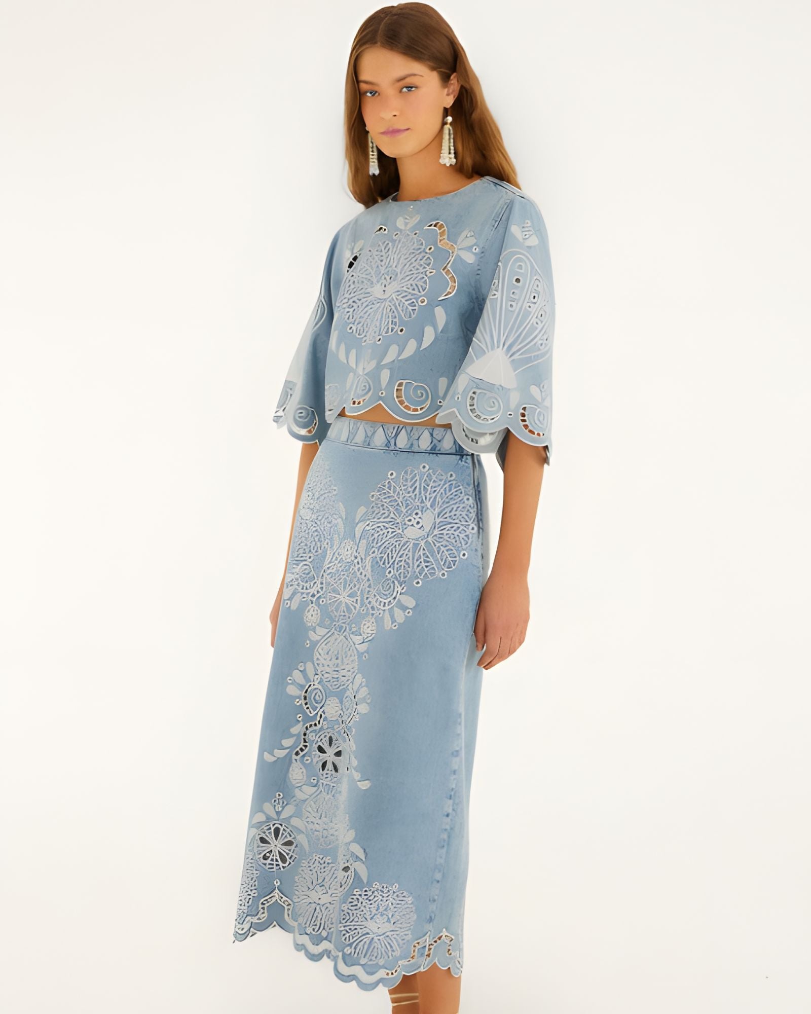 Front view of a model in a studio wearing the FARM Rio denim Richelieu wavy hem midi skirt paired with a matching embroidered top.