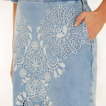 Close-up side view of the Farm Rio denim Richelieu skirt, highlighting the side pocket, zipper closure, and intricate white embroidery.