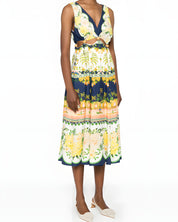 Slight side-angle view of a model in the Farm Rio embellished cutout midi dress, displaying the flowing skirt and delicate hanging drawstring ties.