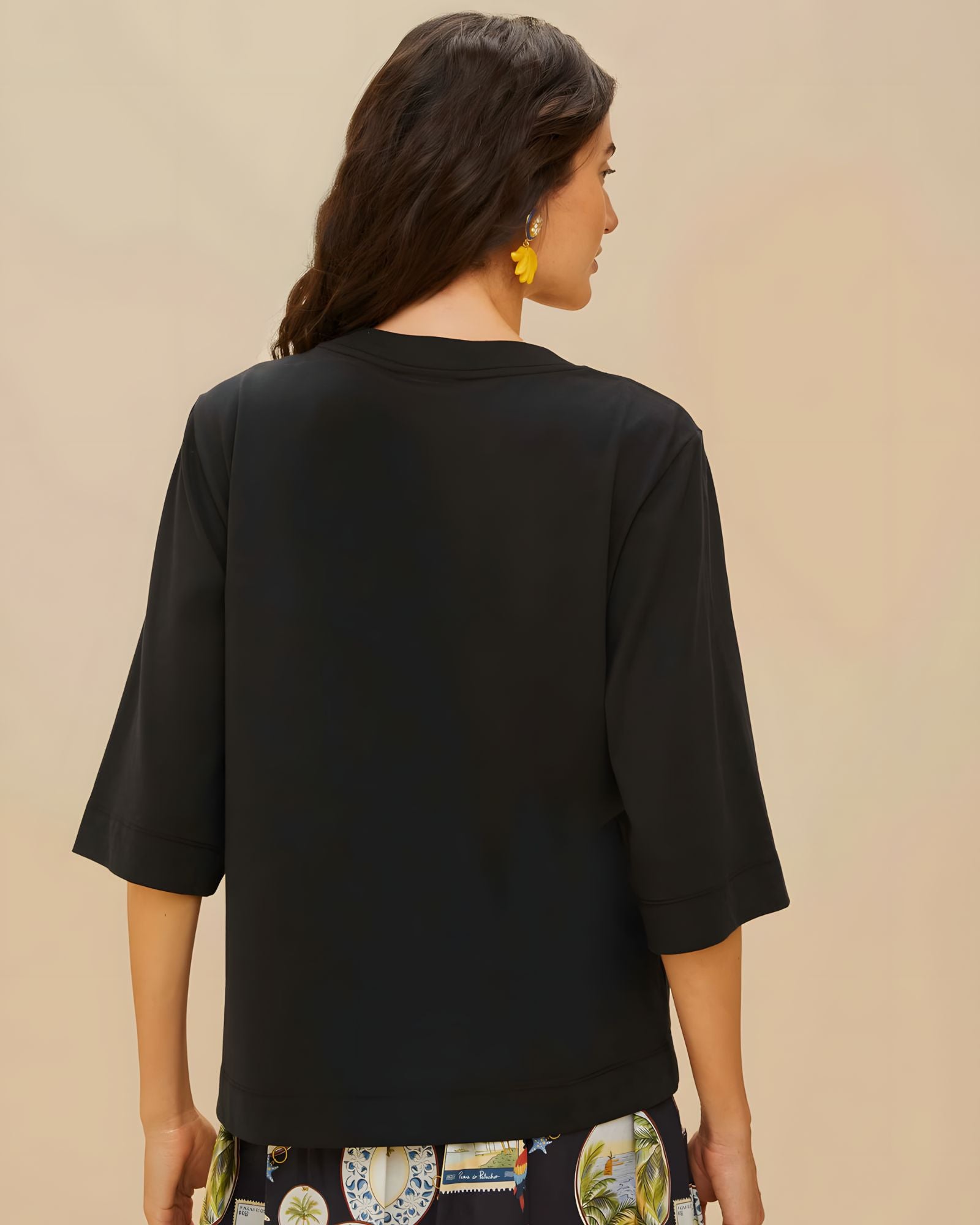 Back view of a model wearing the relaxed fit black FARM Rio organic cotton t-shirt