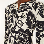 Close-up view of the Farm Rio Off-White Cashews and Birds maxi dress, highlighting the detailed slit V-neckline and artistic contrast print.