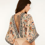 Back view of the model wearing the Farm Rio floral tapestry bodysuit with a deep V-cut back.