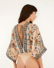Back view of the model wearing the Farm Rio floral tapestry bodysuit with a deep V-cut back.