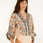 Studio view of the Farm Rio soft pink floral bodysuit highlighting the fit and bottom cut.