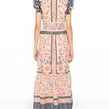 Full-length back studio view of the Farm Rio maxi dress, highlighting the continuous floral pattern, smocked waist detailing, and ruffled shoulders.