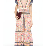 Full-length front view of a model styling the Farm Rio floral tapestry maxi dress, accessorized with a dark clutch bag.