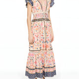Three-quarter studio view of a model wearing the Farm Rio tapestry printed maxi dress, displaying the elegant drape and tiered skirt layout.