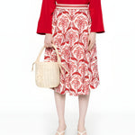 Full-length front view of a model styling the Farm Rio A-line midi skirt with a red top, neutral sandals, and a woven bucket bag.