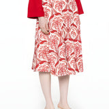 Side studio view of a model wearing the Farm Rio red and white tropical printed midi skirt, paired with a red long-sleeve top.