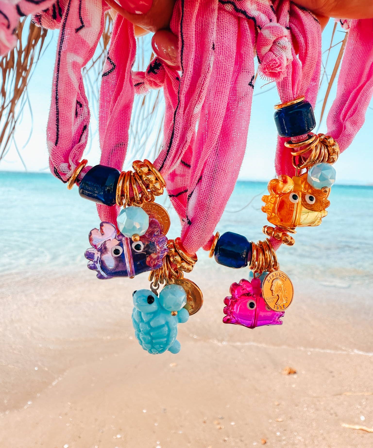 Colorful beaded bandana bracelets with cute crab charms on a beach