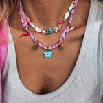 Close-up of the GOUPI pink bandana necklace with star charm, layered with the beaded necklace