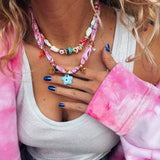 Woman wearing the GOUPI pink bandana necklace layered with the colourful beaded necklace