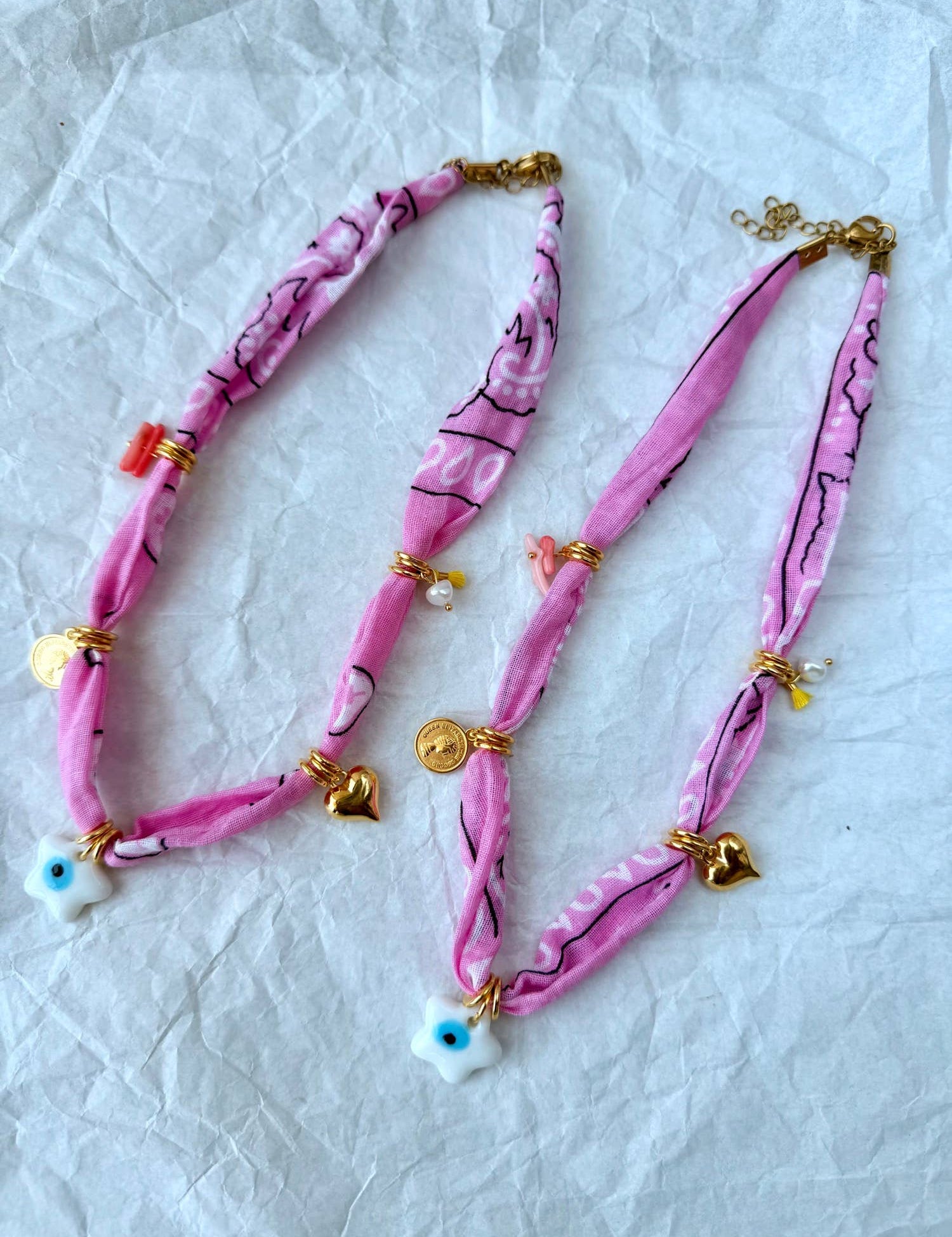 A stacked pile of colorful handmade GOUPI pink bandana necklaces, ready for dispatch from Greece