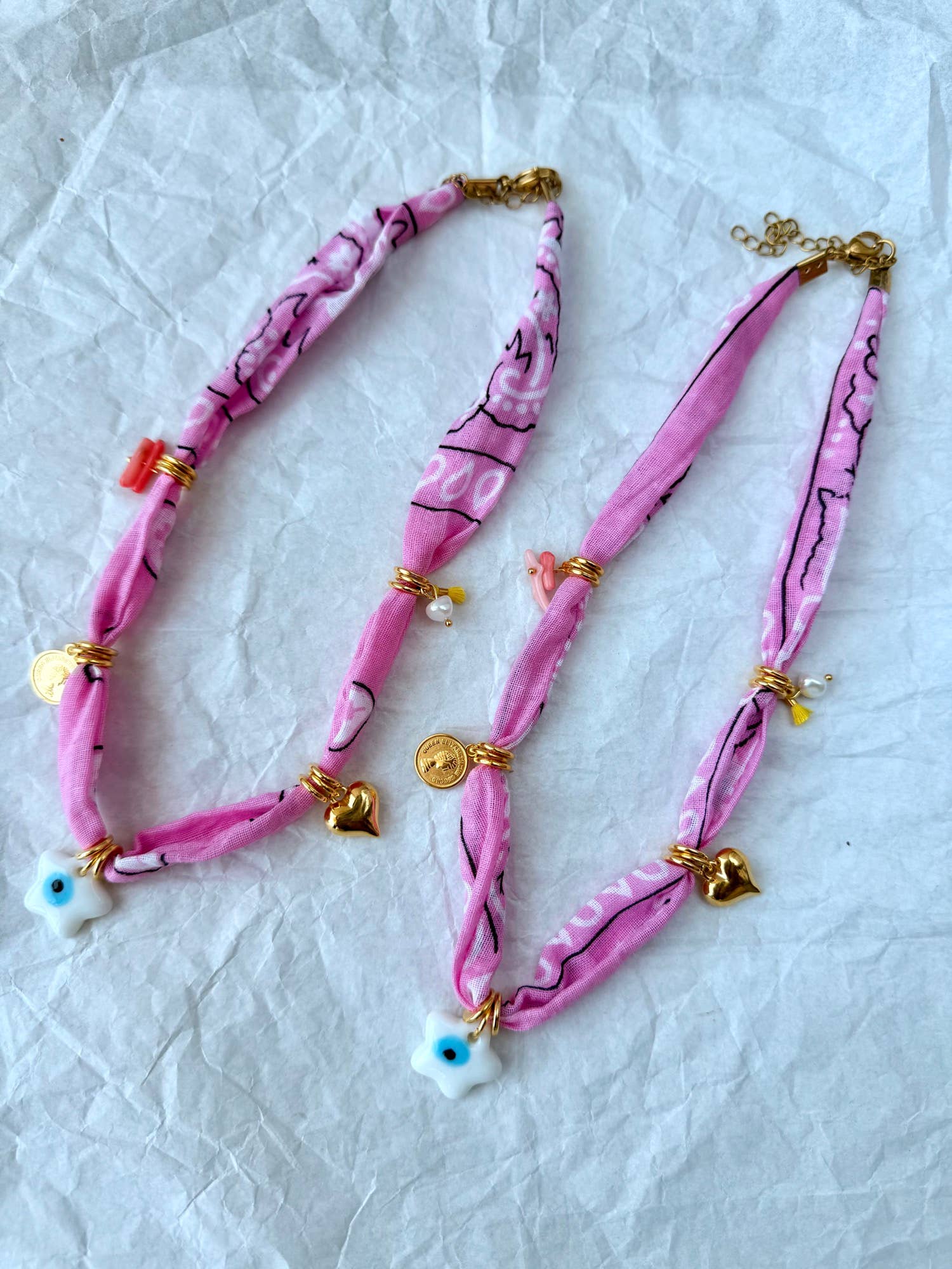 A stacked pile of colorful handmade GOUPI pink bandana necklaces, ready for dispatch from Greece