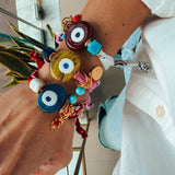 Close-up of a hand wearing colorfu bandana  bracelets with evil eye designs.