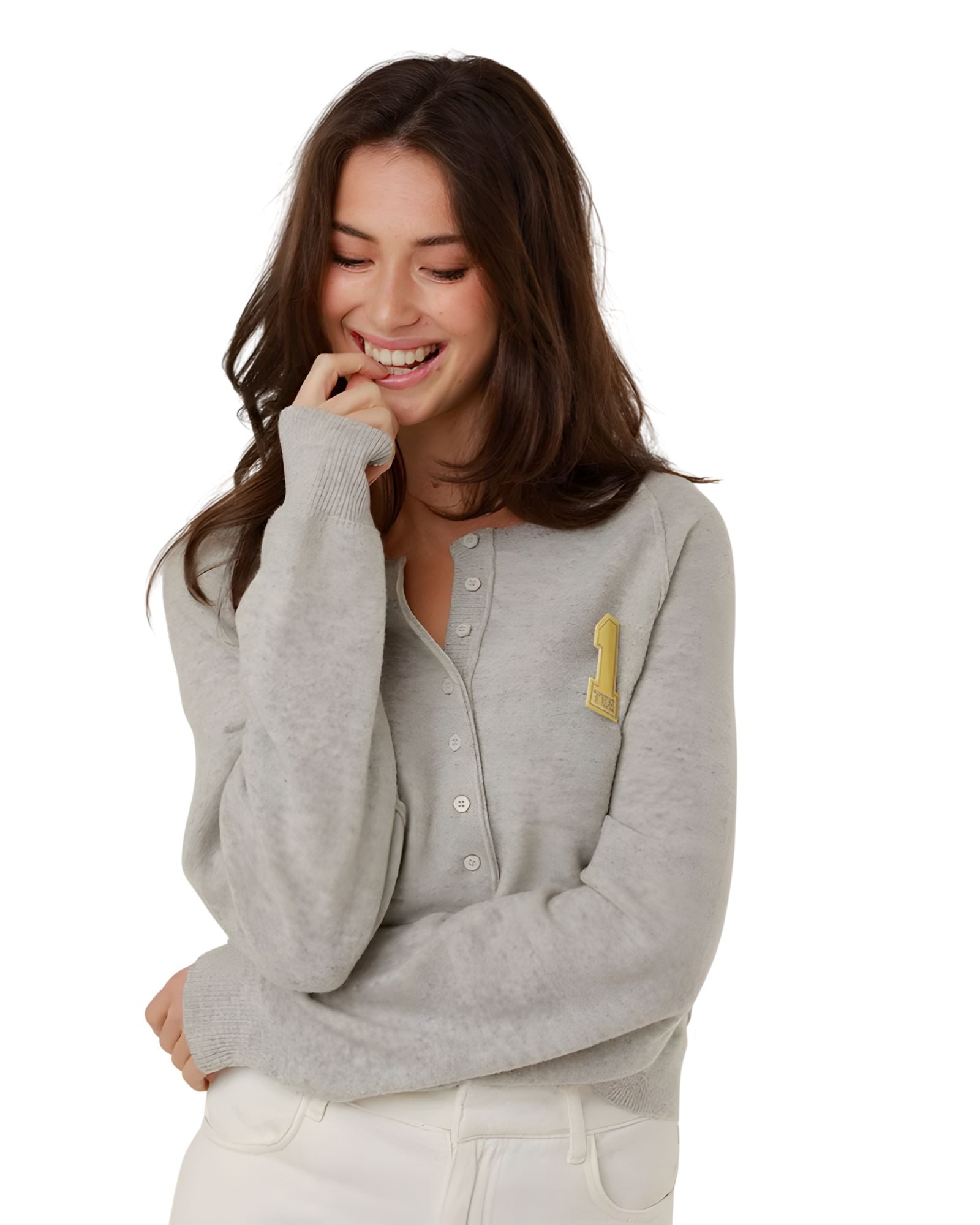 A close-up front view of a smiling woman wearing the classic grey Keila summer fine knit pullover, showcasing the partial buttoned neckline and yellow embroidered collegiate patch.