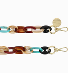 Close-up of the La Coque Française Amber phone chain showing turquoise, tortoiseshell and black resin links with gold-tone clasps.