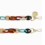 Close-up of the La Coque Française Amber phone chain showing turquoise, tortoiseshell and black resin links with gold-tone clasps.