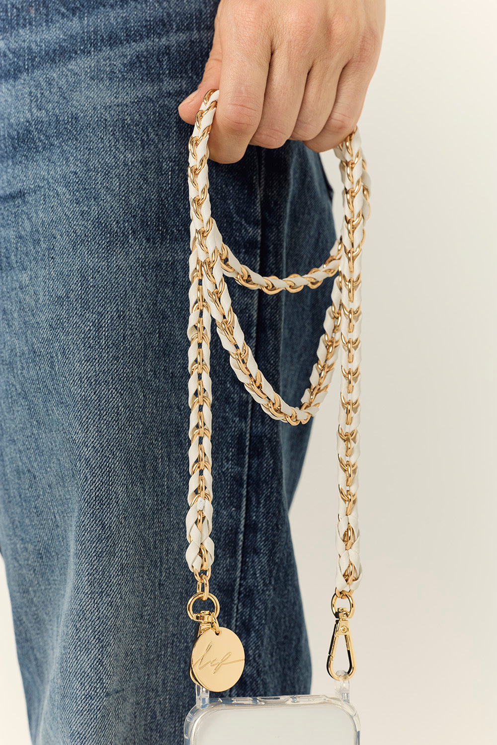 La Coque Française Lou white and gold braided phone chain held with jeans