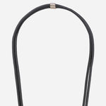 Detail of the gold-tone hardware and signature logo charm on the Nathan black vegan leather strap