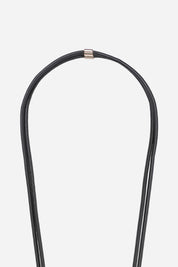 Detail of the gold-tone hardware and signature logo charm on the Nathan black vegan leather strap