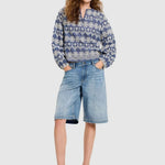 Full body shot of a woman wearing the Lanius blouse styled with denim shorts and sandals.