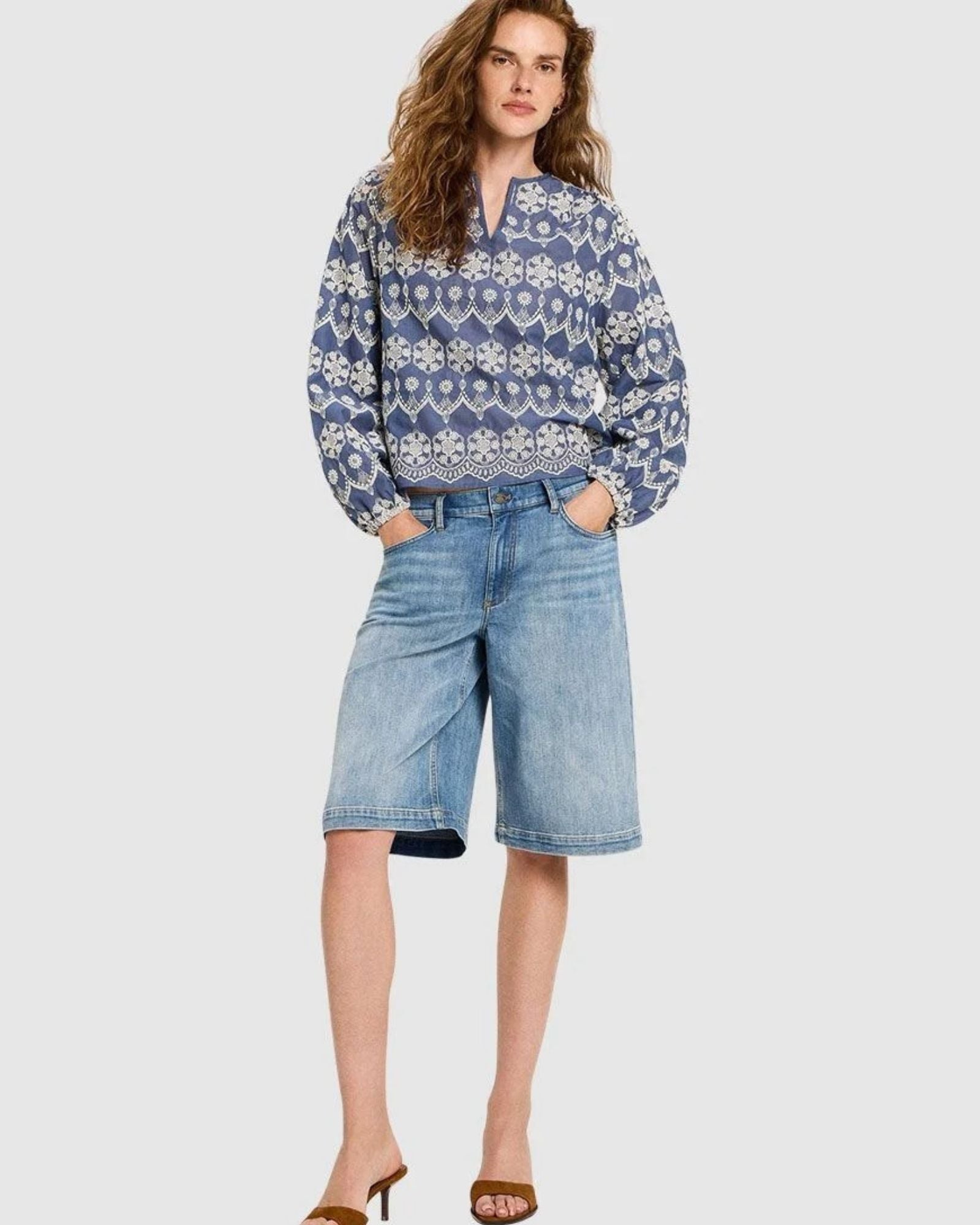 Full body shot of a woman wearing the Lanius blouse styled with denim shorts and sandals.
