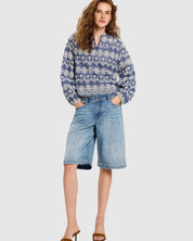 Full body shot of a woman wearing the Lanius blouse styled with denim shorts and sandals.