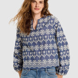 Lanius blue cotton blouse on a female model with long, wavy brown hair, showing the relaxed fit, V-slit neckline, and detailed white embroidery.