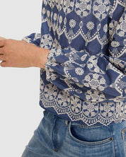 Blue patterned blouse with white lace details worn by a person