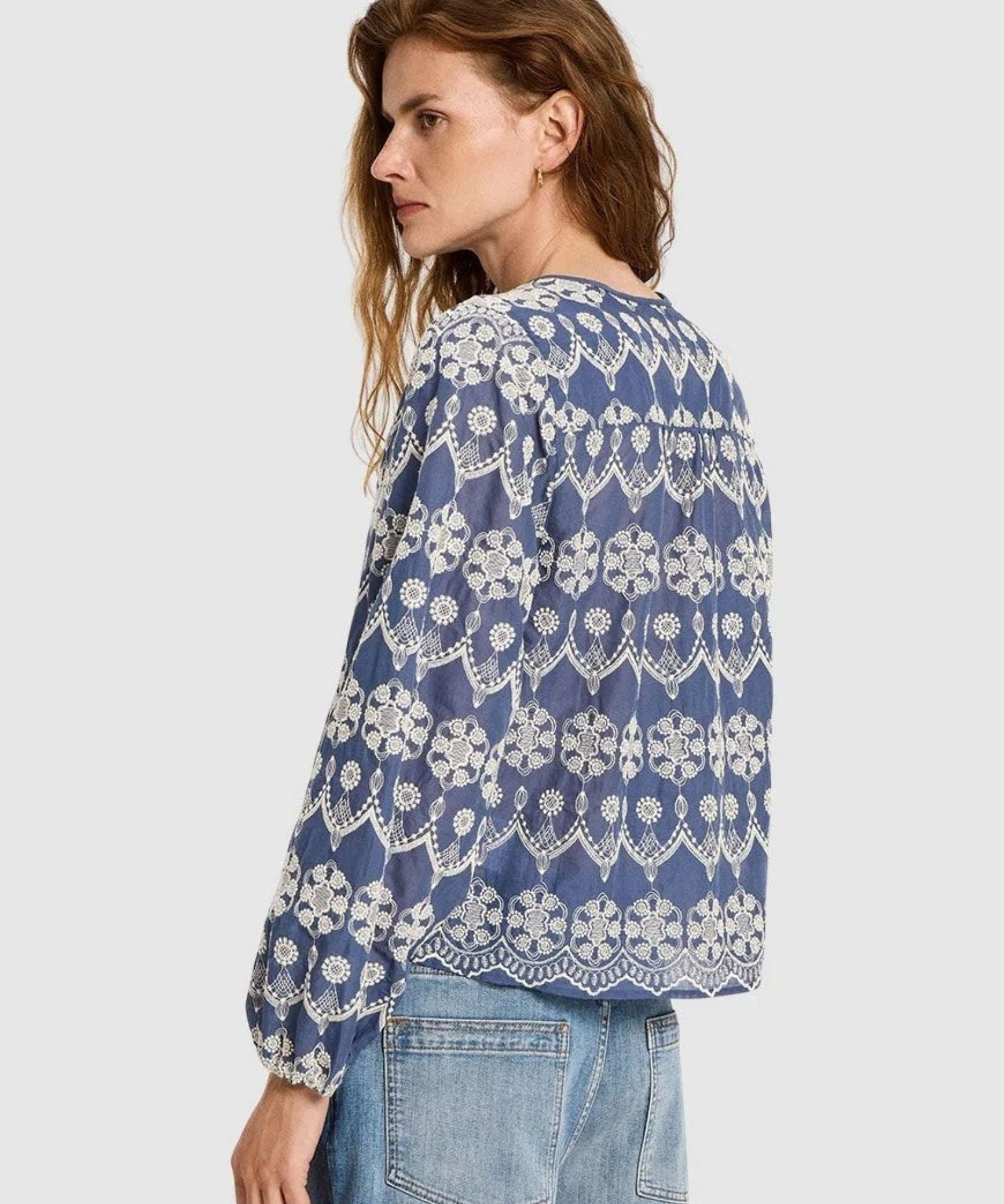 Woman wearing  Lanius blue blouse showing the continuous embroidery pattern