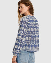 Woman wearing  Lanius blue blouse showing the continuous embroidery pattern