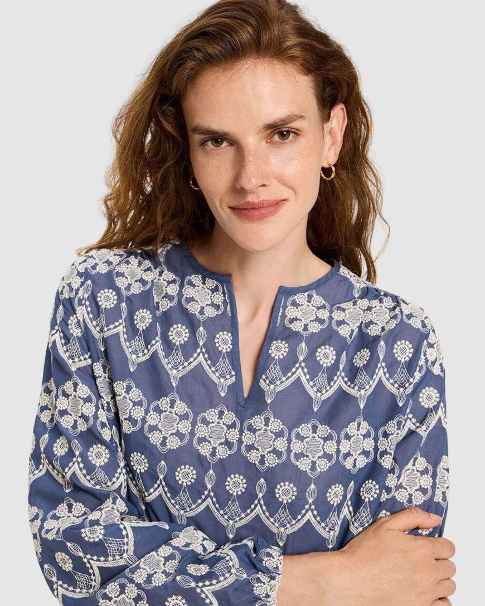 Close-up of the V-slit neckline and intricate white embroidery on the blue cotton.