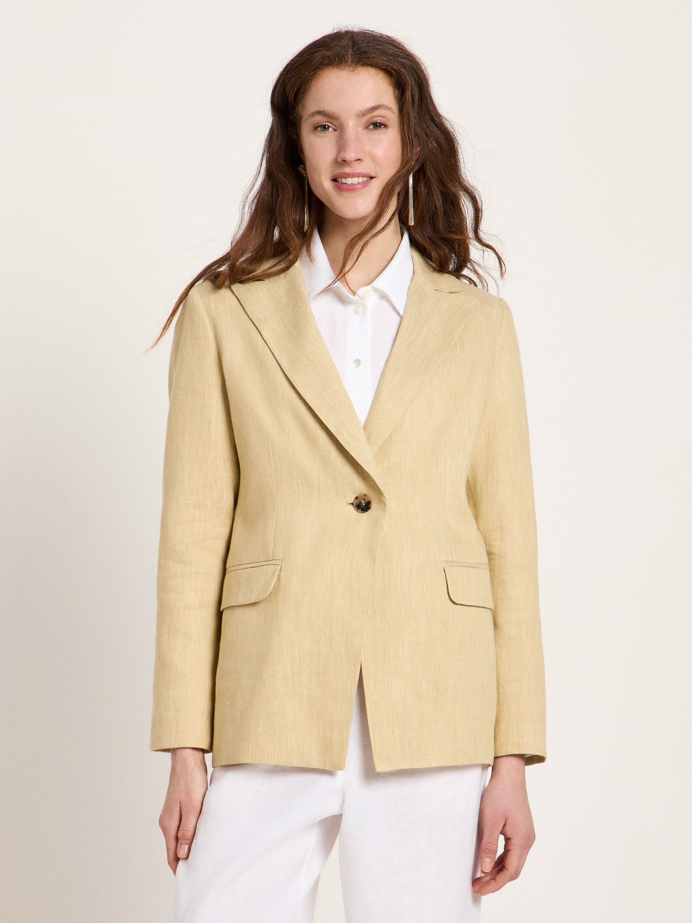 Woman wearing the relaxed-fit LANIUS khaki-creme linen blazer over a white shirt on a plain background