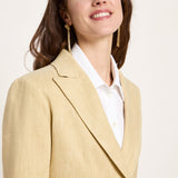 Side angle close-up focusing on the mid-width notched lapel structure, relaxed shoulder fit, and gold statement earrings.