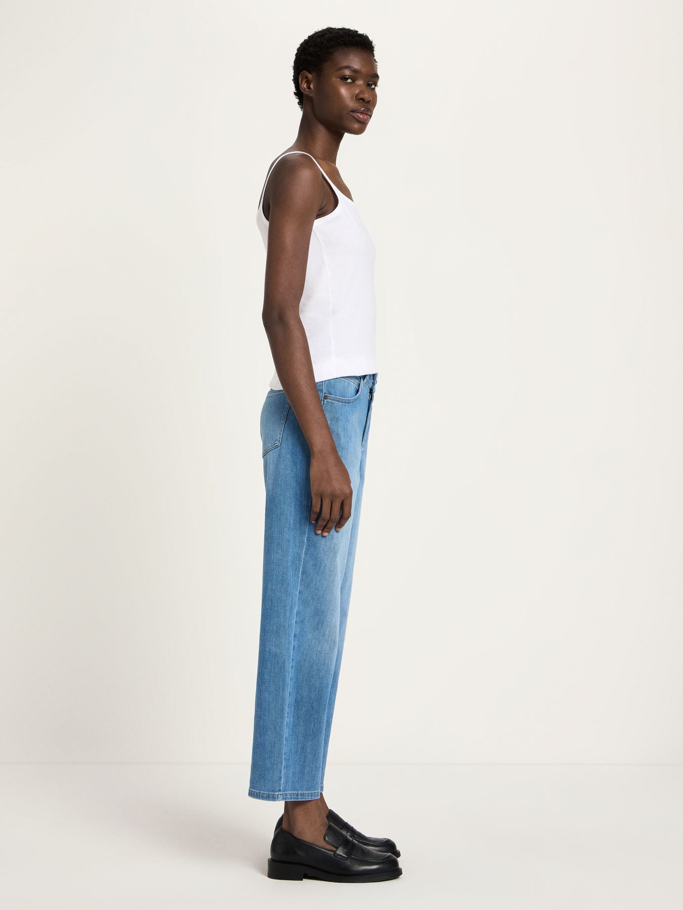 Side profile of a woman wearing Lanius cropped wide-leg jeans in blue, styled for a relaxed sustainable luxury look.
