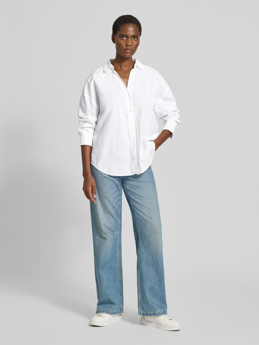 Woman wearing the Lanius oversized white organic cotton shirt paired with blue jeans.