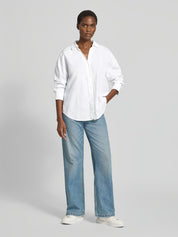 Woman wearing the Lanius oversized white organic cotton shirt paired with blue jeans.