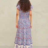 Back view of the tiered Mabe Apparel Della maxi dress in blue and pink artisan print on a model.